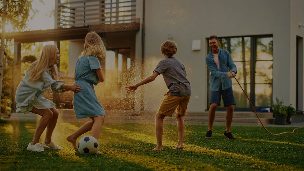 Family playing with soccer ball and hose in front of home